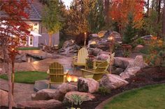 two yellow chairs sitting on top of a lush green field next to rocks and trees