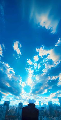 a man sitting on top of a building under a blue sky with clouds in the background