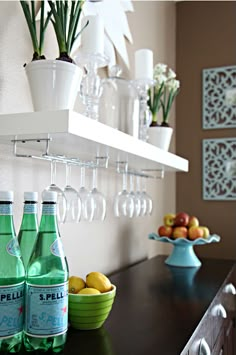 there are many bottles and glasses on the shelf above the counter in this kitchen area