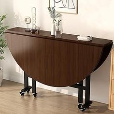 a large wooden table sitting on top of a hard wood floor next to a potted plant