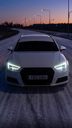 a white car driving down a snow covered road