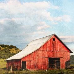 an old red barn sits in the middle of a field