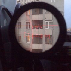 looking through a magnifying glass at an apartment building with red lights in the windows