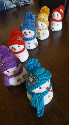 small knitted snowmen sitting on top of a wooden table next to each other