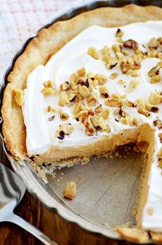 there is a pie with white frosting and nuts on it, ready to be eaten