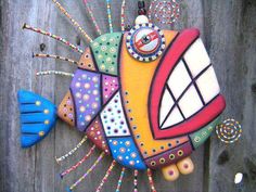 a colorfully painted fish hanging on the side of a wooden fence