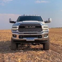 the front end of a silver ram truck parked on top of a dry grass field