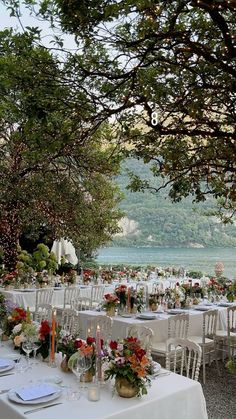 an outdoor dining area with tables, chairs and flowers on the table set for dinner