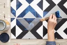 someone using a brush to paint a tile pattern