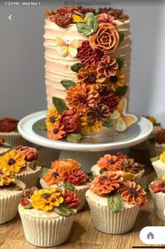 there is a cake with flowers on it and many other cupcakes around it