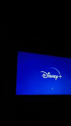 the disney + logo is lit up in the dark with blue light from below it