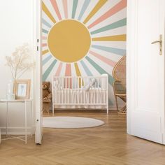 a baby's room with sunburst painted on the wall and wooden floors