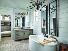 a large white bath tub sitting next to a bathroom sink under a chandelier