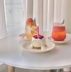 there are two desserts on the table with drinks in front of them and one has a candle