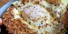 a person holding up a piece of bread with an egg in it and other toppings