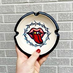 a hand holding a bowl with the rolling stones painted on it's front and side