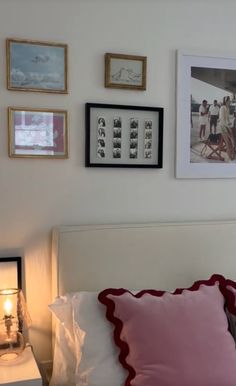 a white bed topped with pillows and pictures on the wall