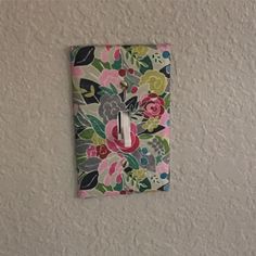 a flowered light switch plate is mounted to the wall with a floral fabric cover