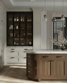 an elegant kitchen with white cabinets and marble counter tops, along with wooden flooring