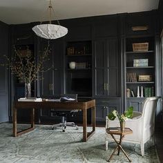 an office with black cabinets and a desk in the middle is decorated with greenery