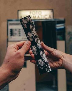 two hands holding an old photo in front of a machine