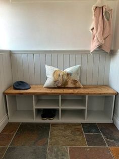 a wooden bench sitting in the corner of a room next to a coat rack and shoes