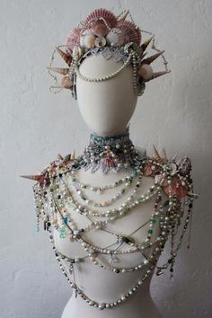 a white mannequin with pearls and seashells on it's head