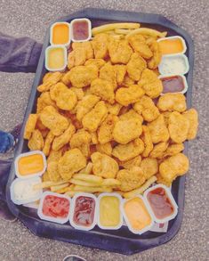 a tray filled with chicken nuggies next to dipping sauces and ketchup