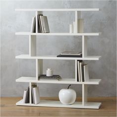 a white book shelf with books and an apple