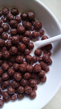 a white bowl filled with chocolate balls and a spoon next to it on a table