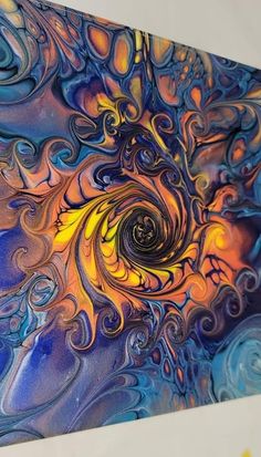 an abstract painting with blue, yellow and orange swirls in the center on a white wall