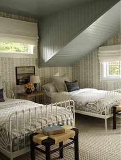 two beds in a bedroom with white walls and carpeted flooring next to each other