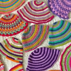 many crocheted hats are arranged on a white surface and one is multicolored