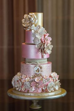 a three tiered wedding cake with pink and white flowers on it's side