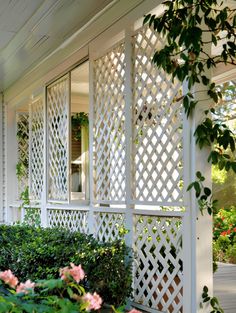 a white house with flowers in front of it and a window on the back wall