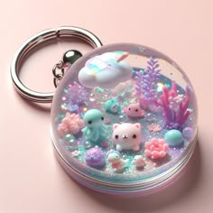 a keychain that has various items inside of it on a pink surface,