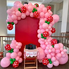 the balloon arch is decorated with strawberrys and polka dot balloons for a birthday party