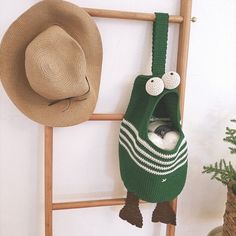 a hat and scarf hanging on the wall next to a ladder with a potted plant