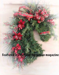 a christmas wreath hanging on the side of a building with red and green bows around it