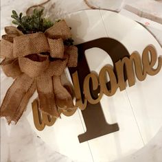 a welcome sign with a burlock bow on it and the word welcome is displayed