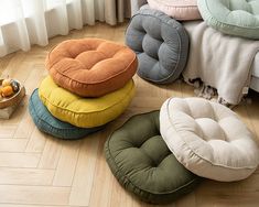 four round cushions on the floor in front of a bed with pillows and fruit bowl