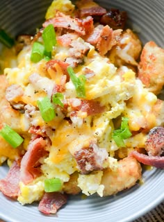 a bowl filled with eggs and bacon on top of a wooden table next to a fork