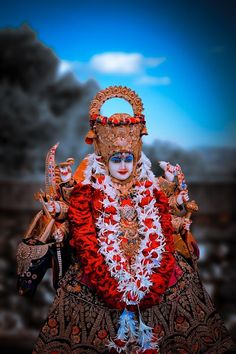 the statue is dressed in red, white and gold colors with an elaborate headdress