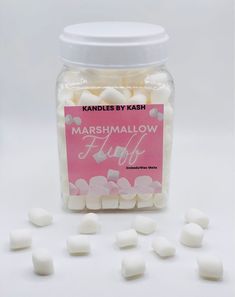 marshmallows in a glass jar on a white surface with pink label and scattered around them