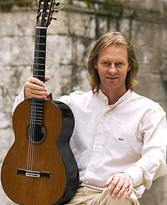 a man holding an acoustic guitar in his right hand