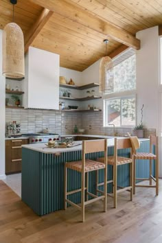 a kitchen with two stools in front of the island and an open window to the outside