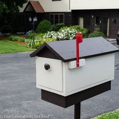 a mailbox in front of a house with a red post on it's side