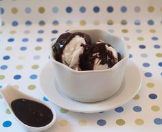 two scoops of ice cream sit in a bowl on a polka dot tablecloth