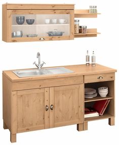 a kitchen with wooden cabinets and white dishes on the shelves above the sink in front of it