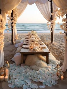 a table set up with flowers and candles on the beach